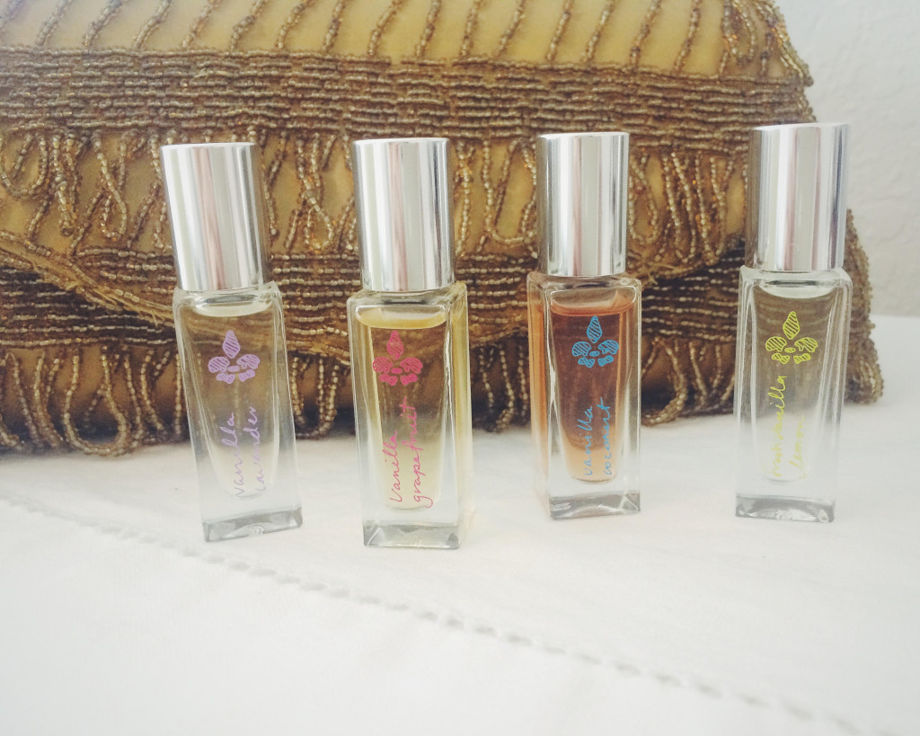 4 small roll-on bottles of Lavanilla perfume in front of gold beaded clutch