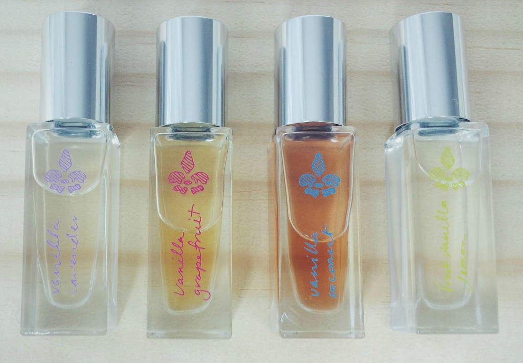 4 small roll-on bottles of Lavanilla perfume laying on wood surface