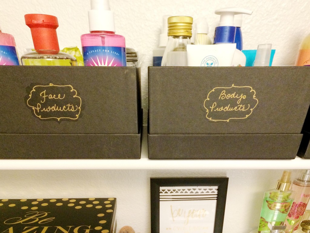 Close up shot of black boxes filled with beauty products with chalkboard label with gold writing