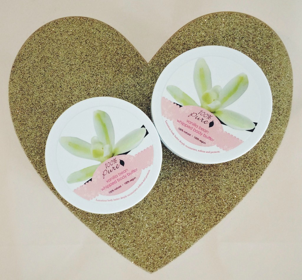 Tubs of 100 percent pure vanilla bean whipped body butter on top of blush and gold heart gift bag