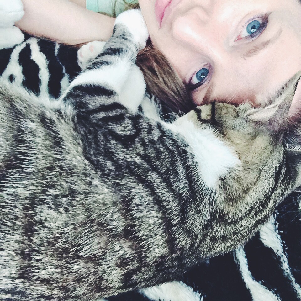girl cuddling with her black and grey striped cat