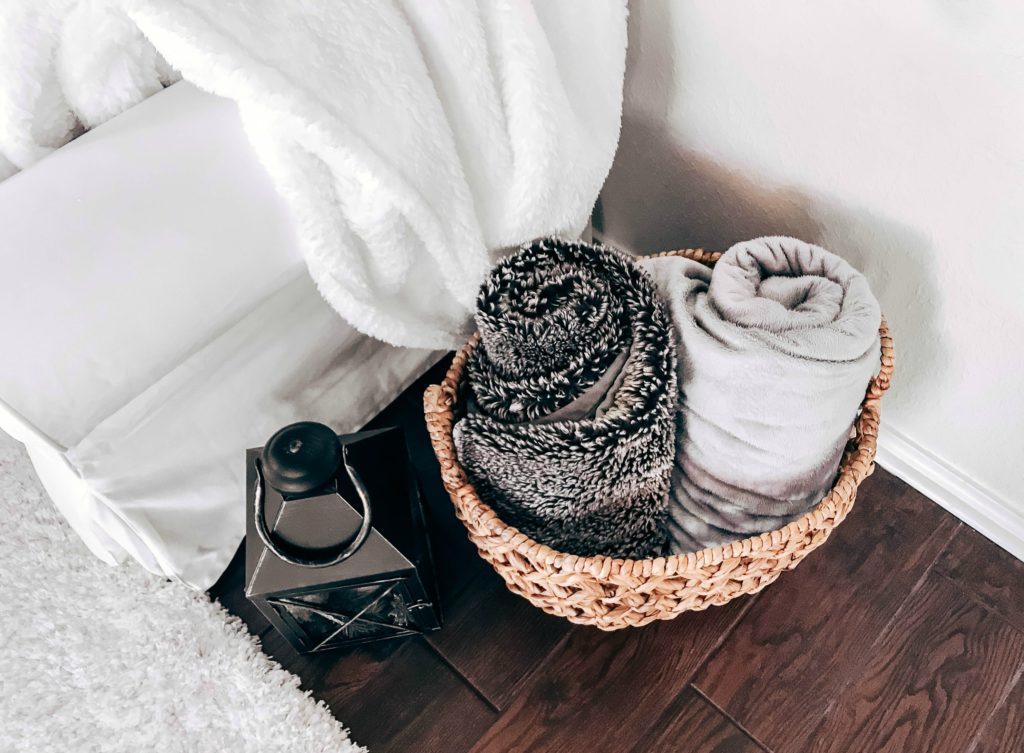 basket of rolled up soft and cozy blankets by couch