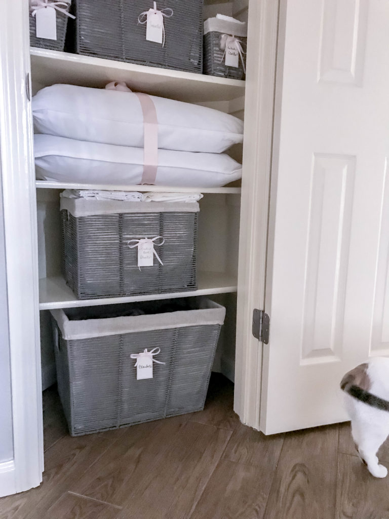 inside view of linen closet with baskets and cat tail in the shot