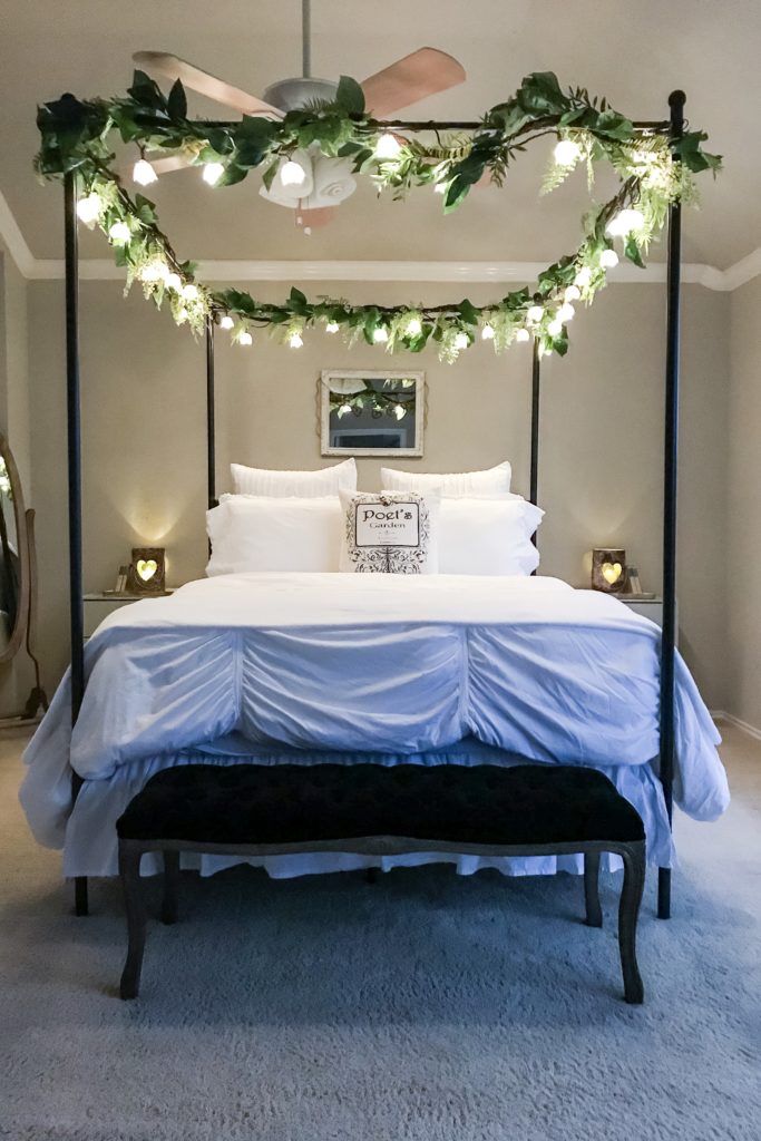 black canopy bed in bedroom with flower fairy lights hanging on top