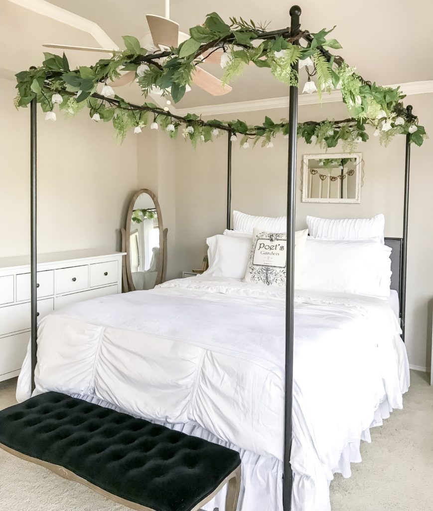 full side view of black canopy bed with white bedding and garlands on top