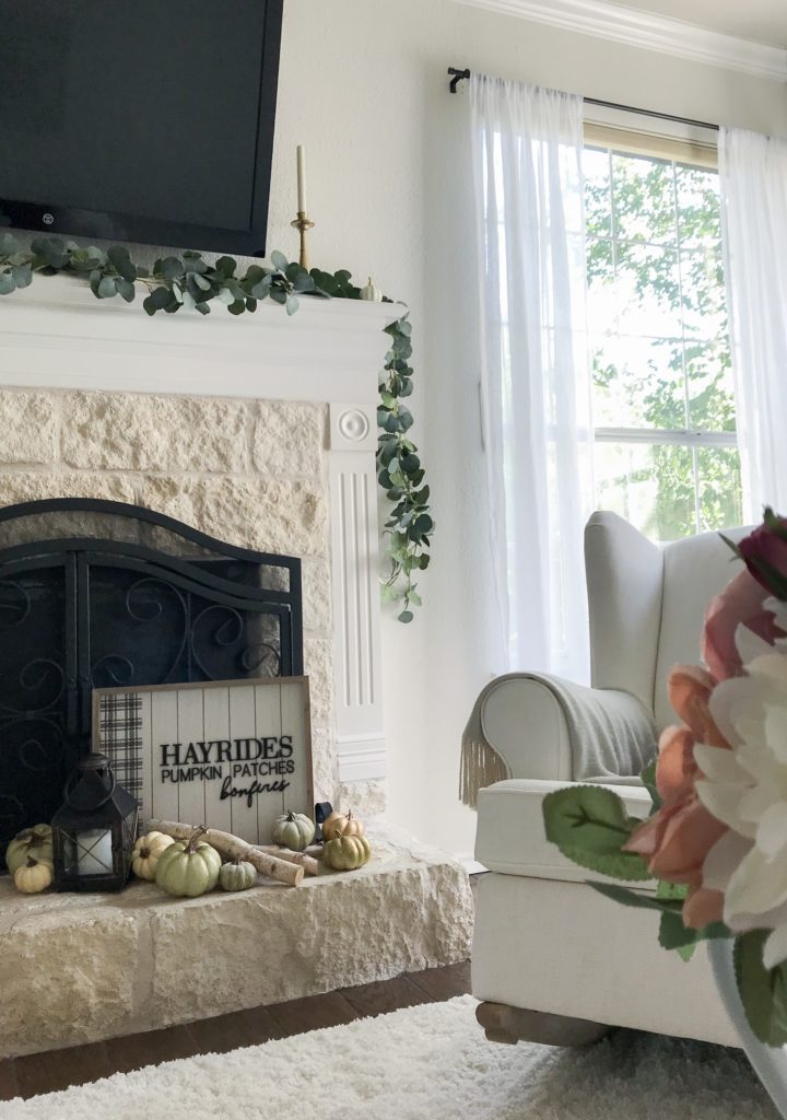 fireplace with fall sign and pumpkins on it and wingback chair by the side for my fall tour